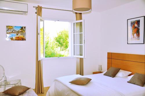 a white bedroom with a bed and a window at Résidence Acqua è Terra 1 in Saint-Florent
