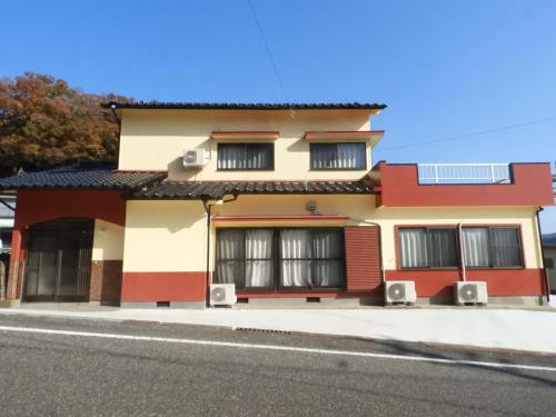 a red and white building with speakers on a street at 一棟貸切の宿 えんの家 in Tsushima