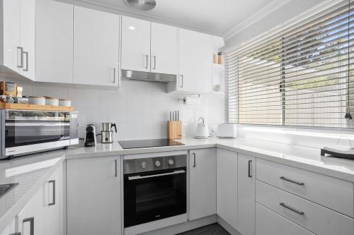 a white kitchen with white cabinets and a window at Riverside Bliss - Luxe Retreat in South Yunderup - Pet friendly in South Yunderup