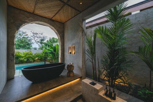 a bathroom with a bath tub and a large window at SIVANA, Hotel Boutique with ocean or garden views - Adults only in Uluwatu