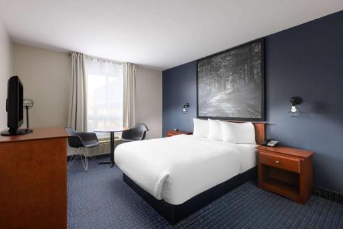 a hotel room with a large bed and a desk at Super 8 by Wyndham Sainte Agathe Des Monts in Sainte-Agathe-des-Monts