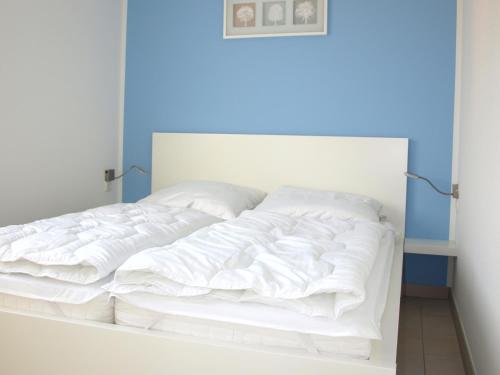 a white bed in a bedroom with a blue wall at Ferienwohnung Graal Müritz im Igelring in Graal-Müritz