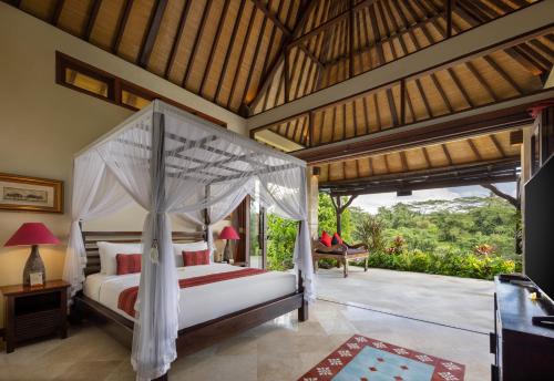a bedroom with a canopy bed and a patio at Bidadari Private Villas & Retreat in Ubud