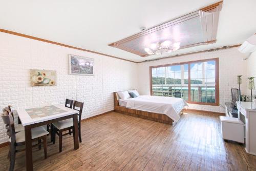 Un dormitorio con una cama y una mesa y una ventana. en Ganghwa Ara Pension, en Incheon