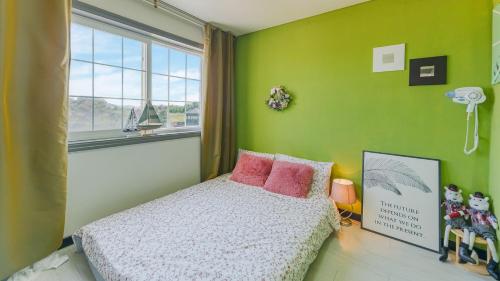 a bedroom with green walls and a bed with pink pillows at Ganghwa Rodemhouse Pension in Incheon