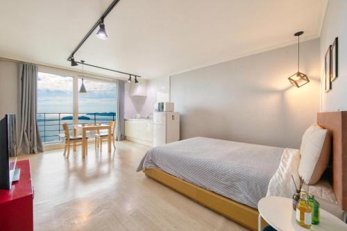 a bedroom with a bed and a table and a kitchen at Yeosu Harushimpyo Pension in Yeosu
