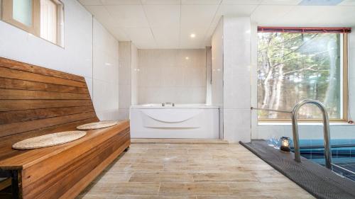 a bathroom with a tub and a sink and a window at Gapyeong Namian Pool Villa in Gapyeong