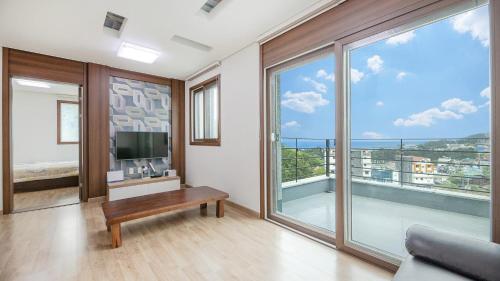 a living room with a television and large windows at Samcheok Santorini Pension in Samcheok