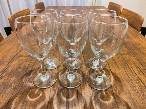 four empty wine glasses sitting on a wooden table at Sakuradai House in Ichihara