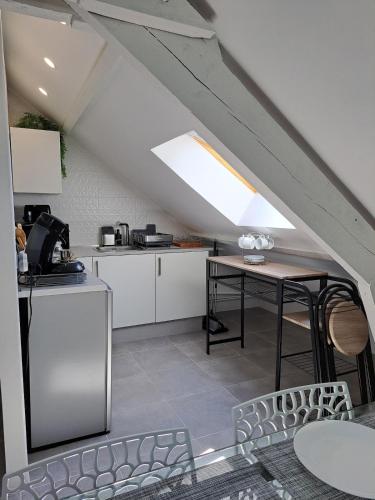 une cuisine mansardée avec des placards blancs et une table dans l'établissement Modern cozy 3 rooms flat between Disney and Paris, à Roissy-en-Brie