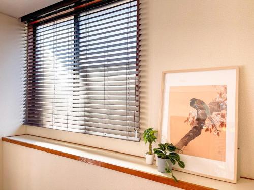 a window with a picture and a plant on a window sill at Sakuradai House in Ichihara