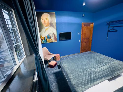 a blue bedroom with a bed and a painting at Broken bed hootel in Kaunas