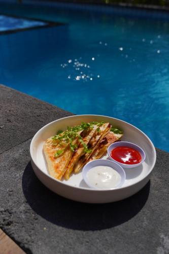 a plate of food on a table next to a pool at Sadev Resort in Gili Trawangan