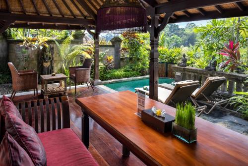 a patio with a table and chairs and a pool at Bidadari Private Villas & Retreat in Ubud