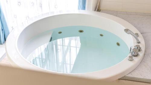 a bath tub with a round mirror in a bathroom at seonjaedo secret spa pension in Incheon