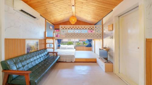 a green couch in a room with a bedroom at Pohang Puleungolae Caravan in Pohang