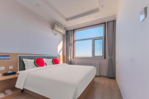 北京市にあるBeijing Watermelon Journey Hotel - Daxing Airportの赤い枕が付いた大きな白いベッドのある寝室