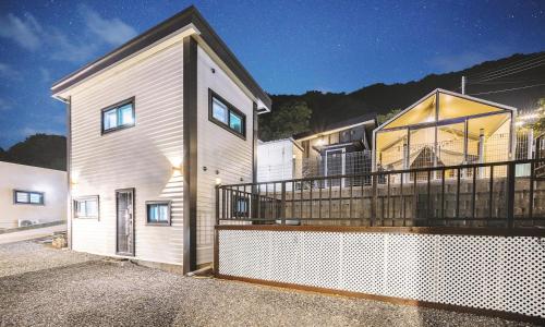 a white house with a balcony at night at Gapyeong Ddobagi Pet & Spa Glamping in Gapyeong