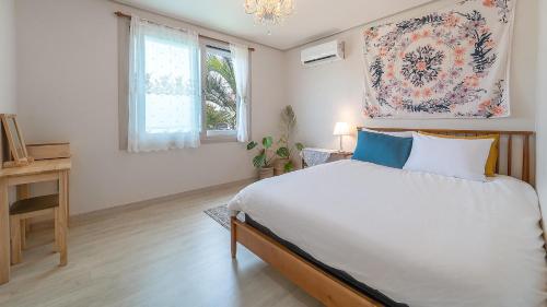 a bedroom with a large bed and a window at lalapipo jeju in Jeju