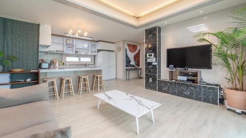 a living room with a couch and a tv and a table at lalapipo jeju in Jeju