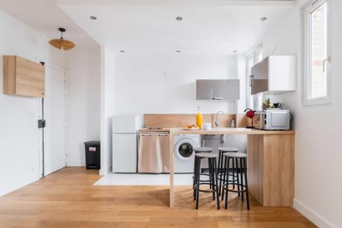 une cuisine avec une machine à laver et un comptoir avec des tabourets dans l'établissement Appartement 60m2 Bien Amenage- Paris 12 - 4p - FLAT-GUEST, à Paris