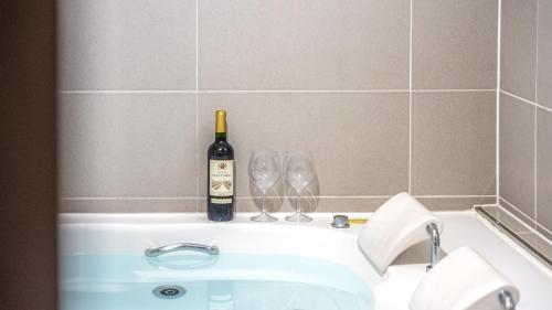 a bottle of wine and two wine glasses on a bath tub at Gapyeong Lemon Pension in Gapyeong