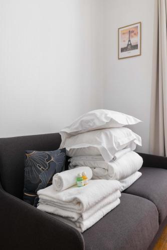 une pile de serviettes et d'oreillers sur un canapé dans l'établissement Studio equipe centre nation - Paris 12 - 2P - FLAT-GUEST, à Paris