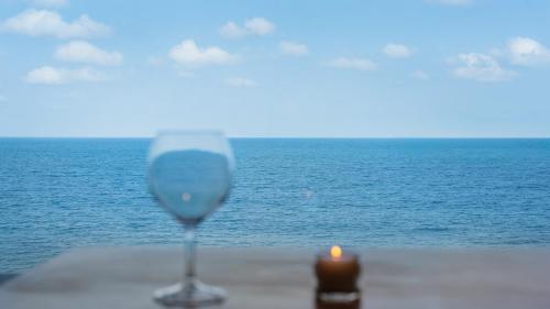 a candle and a wine glass on a table near the ocean at Sokcho Moreve Pension in Sokcho