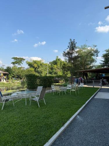 a group of chairs and tables on the grass at theriverhouse in Ban Muang Nga