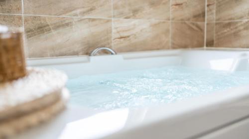a bath tub filled with blue water in a bathroom at daebudo idea ocean view pension in Ansan