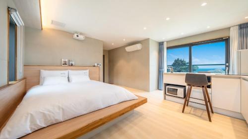 Un dormitorio con una cama y un escritorio con una silla. en Gyeongju Adria Stay Pension, en Gyeongju