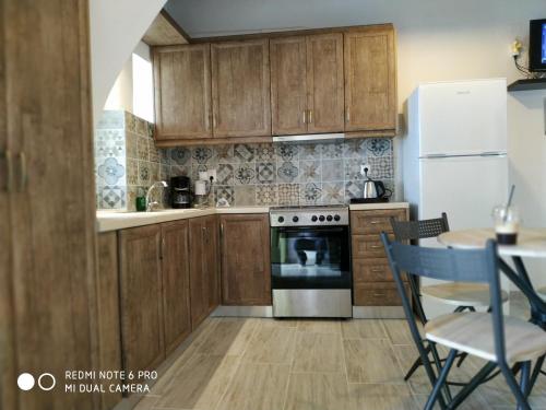 cocina con armarios de madera, nevera y mesa en Sigalas House, Sikinos Island, en Síkinos