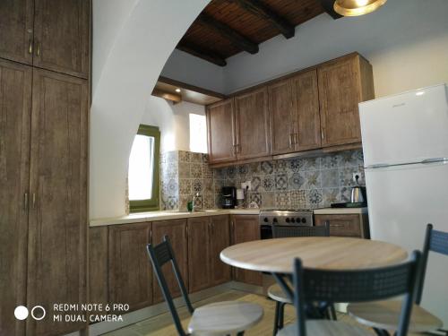 Una cocina con gabinetes de madera y una mesa con sillas. en Sigalas House, Sikinos Island, en Síkinos