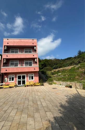 a large pink building with benches in front of it at Bei Ao Bi Shan Jyu in Dongyin