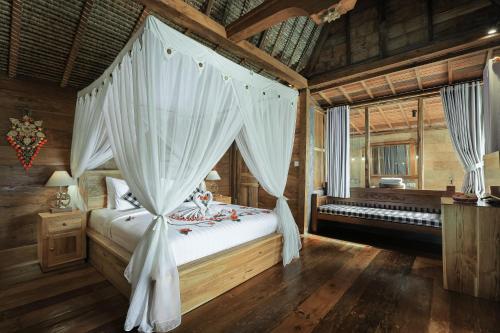 a bedroom with a canopy bed with white curtains at Lawani Resort in Tegalalang
