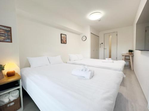 two beds in a room with white sheets at Sanctuary Residence難波桜川 in Osaka