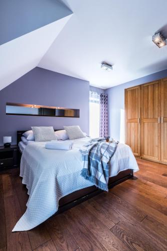 a bedroom with a large bed with blue walls and wooden floors at Villa 64 Zakopane in Zakopane