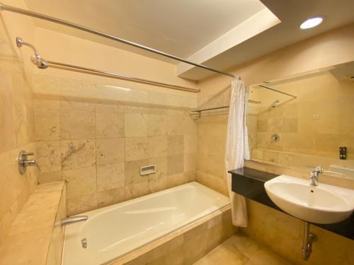a bathroom with a sink and a bath tub and a sink at Newly Renovated 3BR with Smart TV Braga City Walk Apartment By Travelio in Bandung