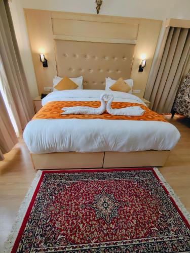 a bedroom with a large bed with a red rug at Sangaylay palace in Leh