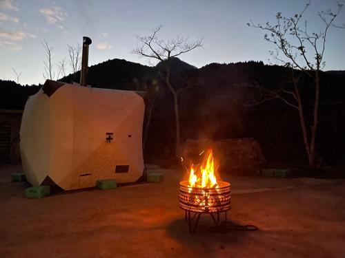 a fire in a barrel in front of a tent at Tabinoyado Asonoyu in Aso