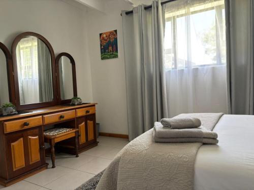 a bedroom with a bed and a dresser and a mirror at Dassen Cove Self Catering in Plettenberg Bay