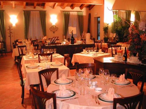 a restaurant with white tables and chairs with wine glasses at Magnagallo in Campogalliano