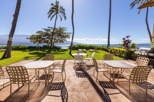 a patio with tables and chairs and palm trees at Makani A Kai Resort B-7 in Wailuku