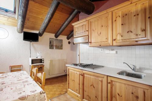 a kitchen with wooden cabinets and a sink and a table at Casa Chamonin Pila in Gressan