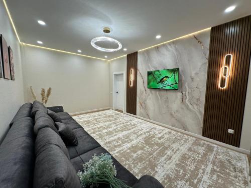 ein Wohnzimmer mit einem Sofa und einem Fernseher an der Wand in der Unterkunft В шикарном районе Атырау возле дворца ЦЕНТР АБАЯ New City от аэропорта 3 минуты in Atyrau