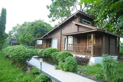 a small wooden house with a porch and a walkway at Jironi Resort in Tezpur