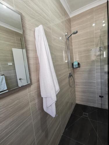 a bathroom with a shower with a white towel at Three Bedrooms House in Chullora