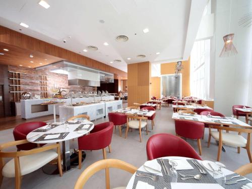 a restaurant with tables and chairs and a kitchen at Novotel Jazan in Jazan