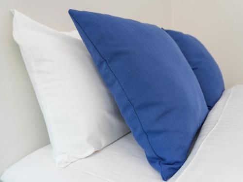 a blue pillow and two white pillows on a bed at OUCHI HOTEL Onaganishi in Hiroshima