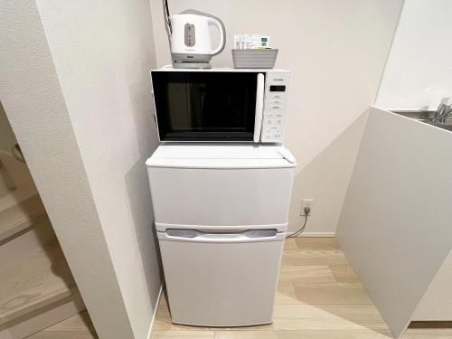 a microwave oven sitting on top of a refrigerator at OUCHI HOTEL Onaganishi in Hiroshima